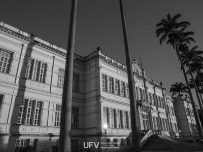 Foto em preto e branco de um grande prédio de dois andares, com muitas janelas altas e grande escadaria em frente. 