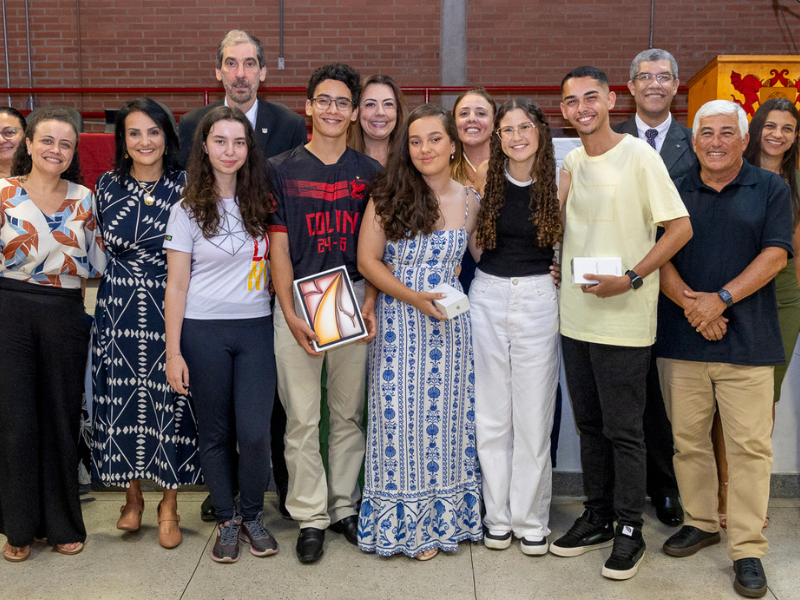 5 jovens, 6 mulheres de meia-idade e 3 homens idosos de pé lado a lado, sorrindo para a foto. 