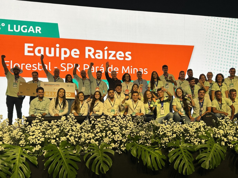 Dezenas de homens e mulheres jovens, lado a lado em duas fileiras, todos de camisa amarela de manga longa. 