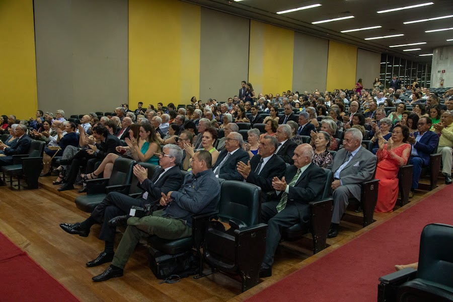 Foto do auditório lotado, durante a cerimônia. As pessoas estão aplaudindo. 