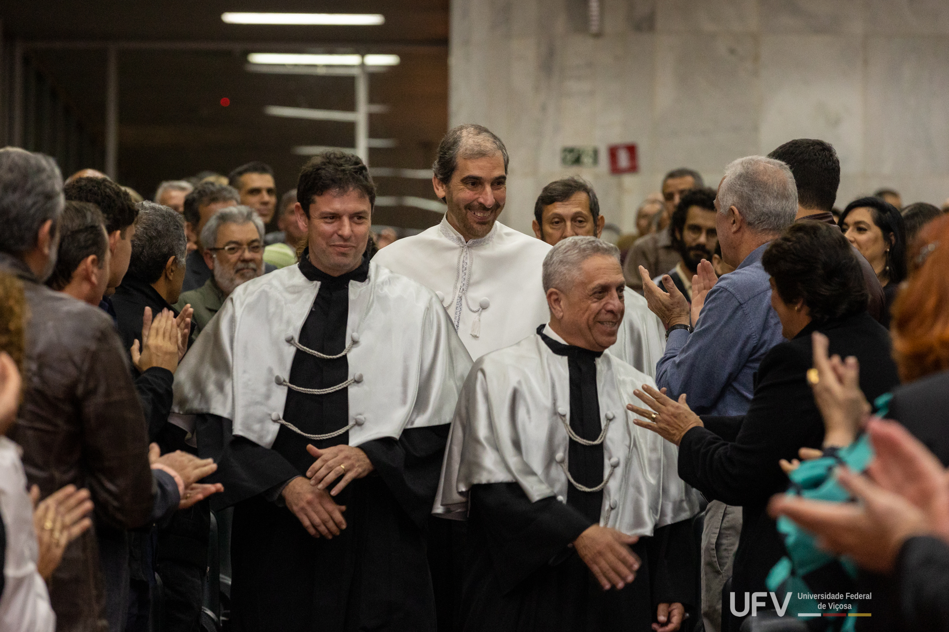 Reitor, vice-reitora e diretores os Centros de Ciências fazendo sua entrada pelo corredor do auditório. 