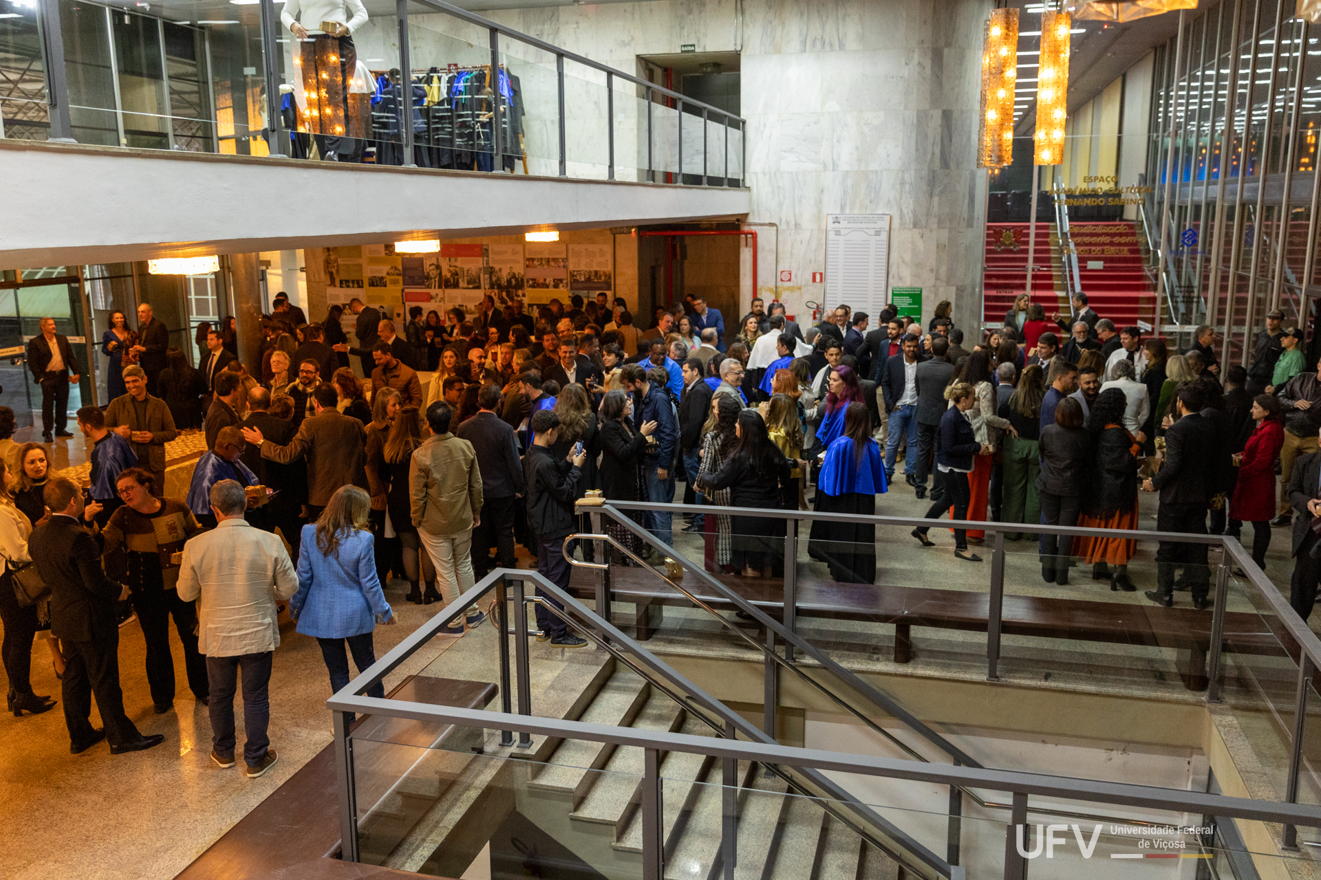 Hall de entrada do auditório, com grande número de pessoas cumprimentando as autoridades recém-empossadas. 