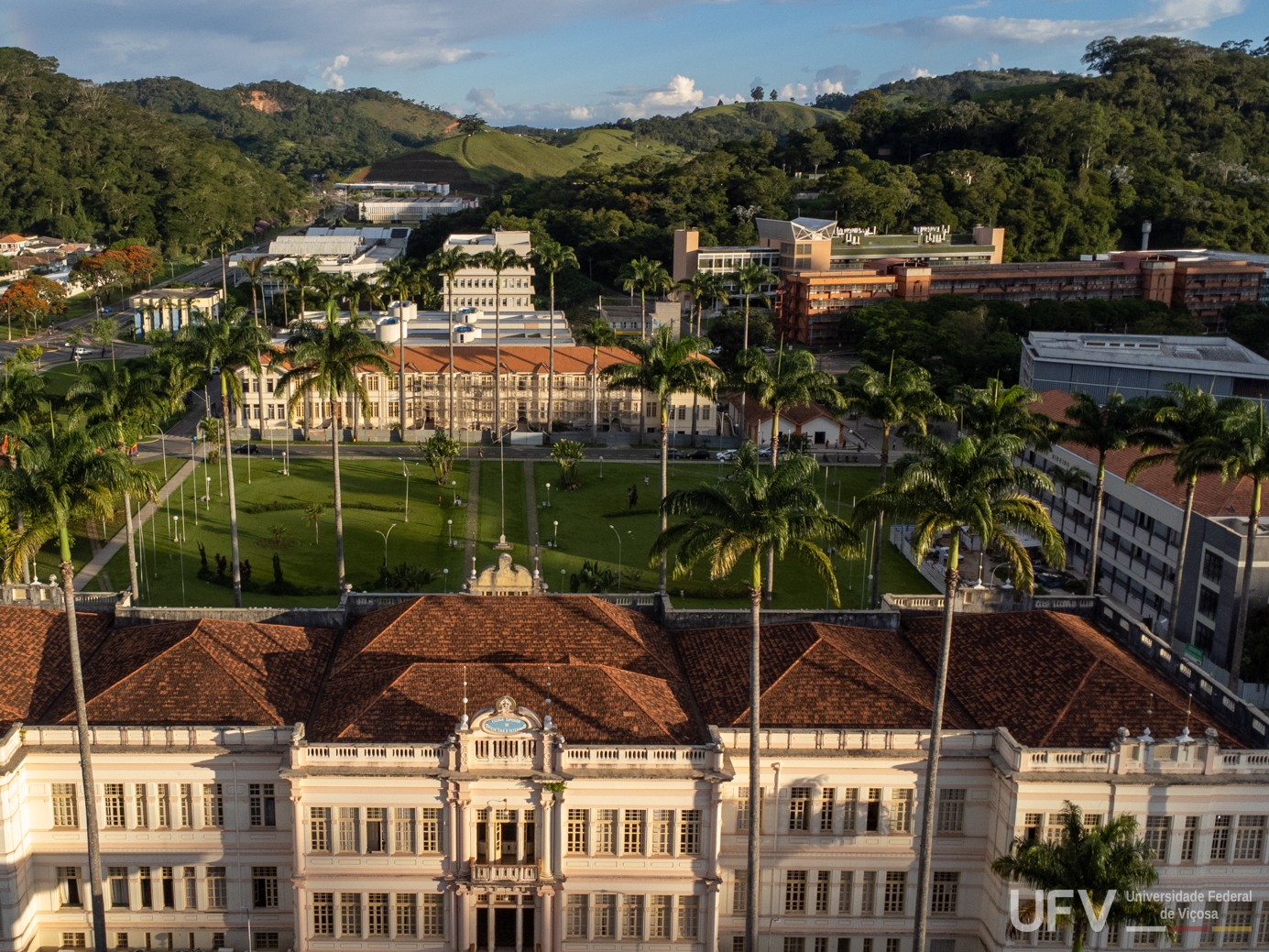 Foto aérea de parte do campus Viçosa, onde se vê o prédio principal, o alojamento antigo e o grande gramado entre eles. 