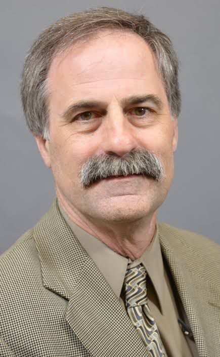 Richard era um homem idoso, branco, olhos claros, cabelo liso grisalho e bigode farto e também grisalho. 