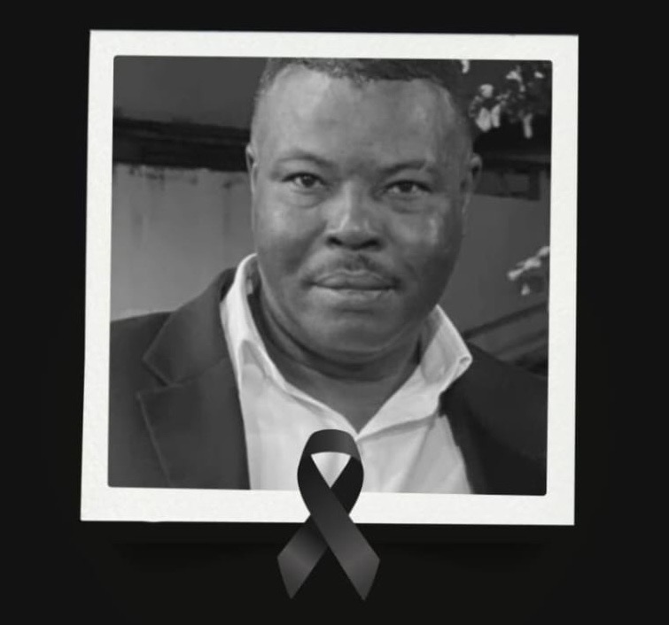 Homem negro, de meia-idade, cabelos curtos e bigode, olhos ligeiramente puxados. 